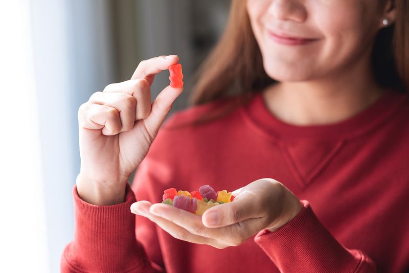 Frau, hält Gummibärchen in die Kamera.