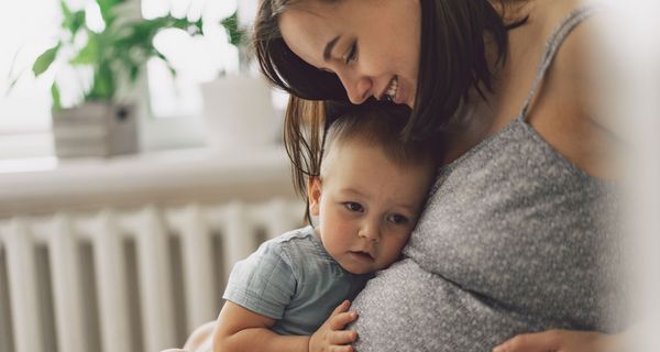 Kleiner junge horcht am Bauch seiner schwangeren Mutter.