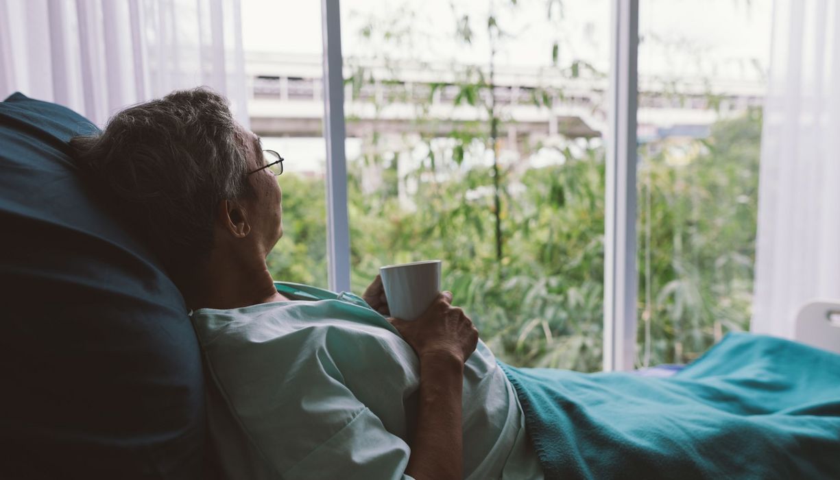 Älterer Mann, liegt in einem Krankenhausbett.