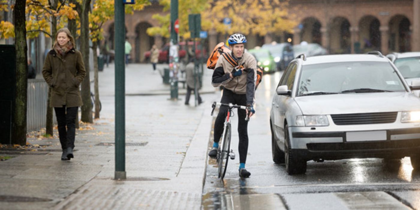 Auto und Fahrradfahrer warten an einer roten Ampel