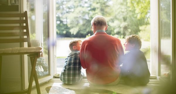 Älterer Mann, sitzt mit zwei Jungen auf einer Treppenstufe.