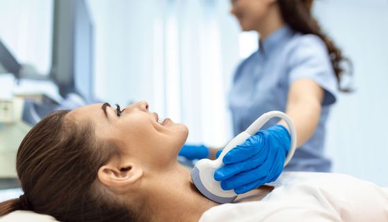 Frau, erhält einen Ultraschall ihrer Schilddrüse