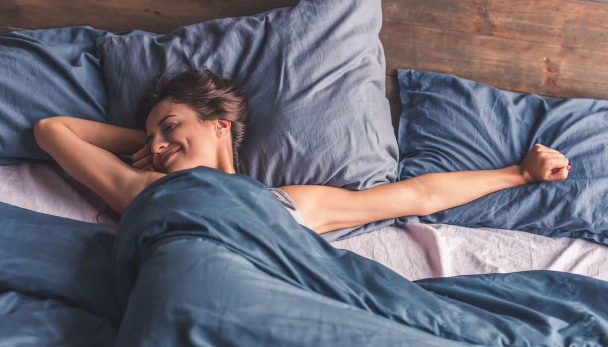 Junge Frau, räkelt sich am Morgen in ihrem Bett.