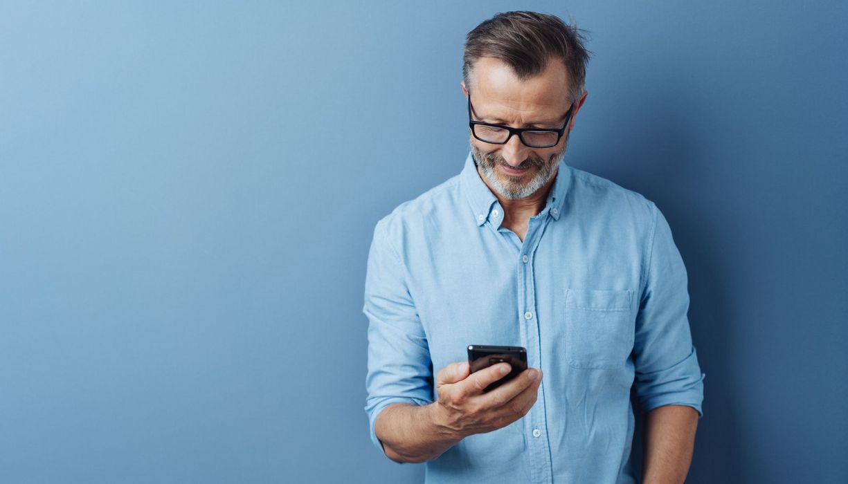 Mann, hält ein Smartphone in der Hand.