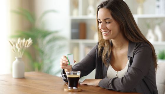 Junge Frau süßt ihren Kaffee mit Süßstoff
