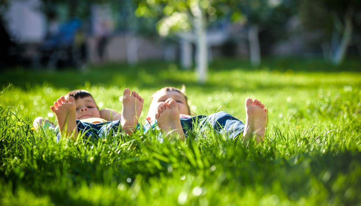 Zwei Kinder liegen auf einer Wiese.