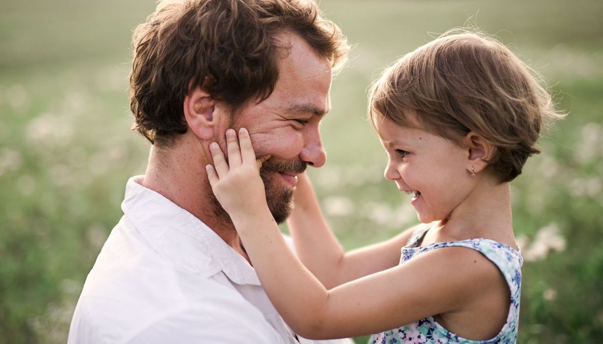 Vater mit Tochter, die sein Gesicht streichelt.