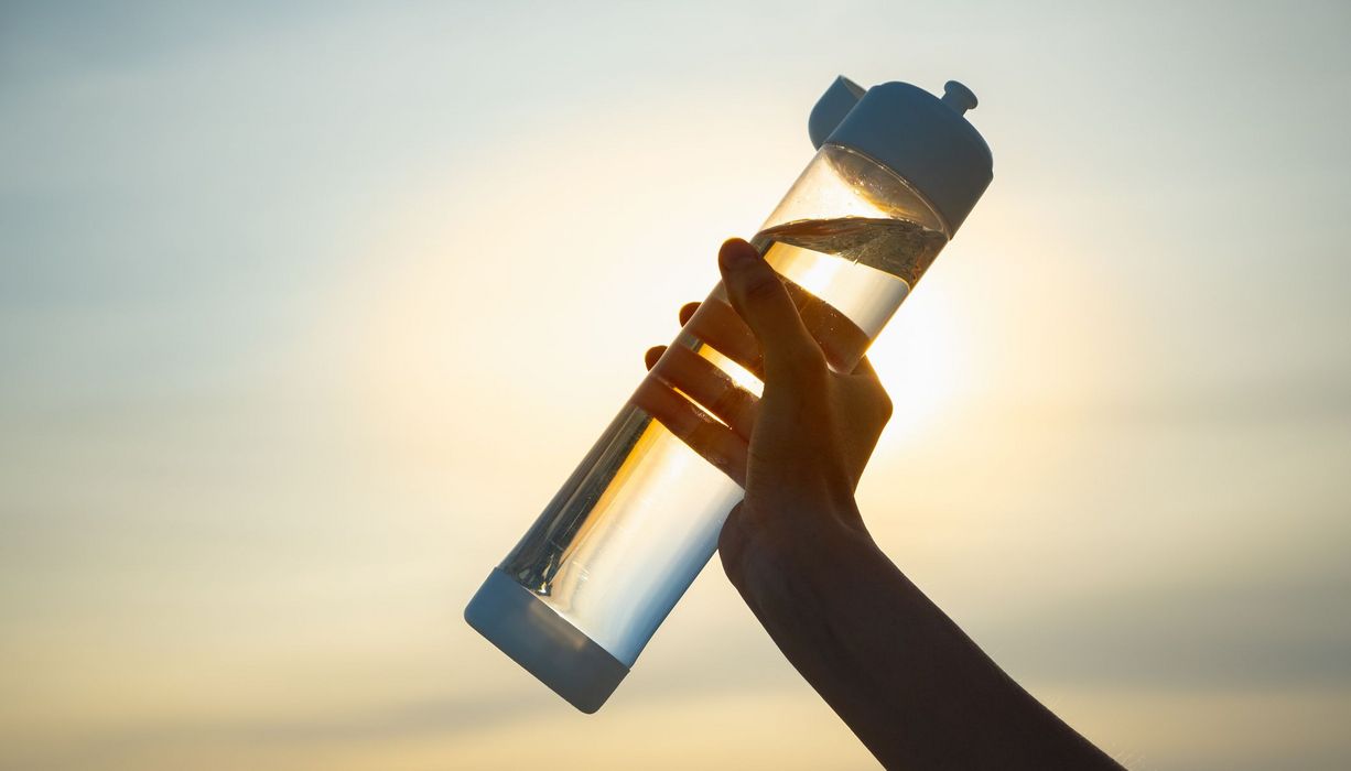 Frau, hält eine Trinkflasche in die Luft.