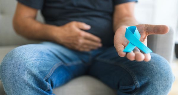 Mann, hält eine blaue Schleife als Symbol für Prostatakrebs in der Hand.