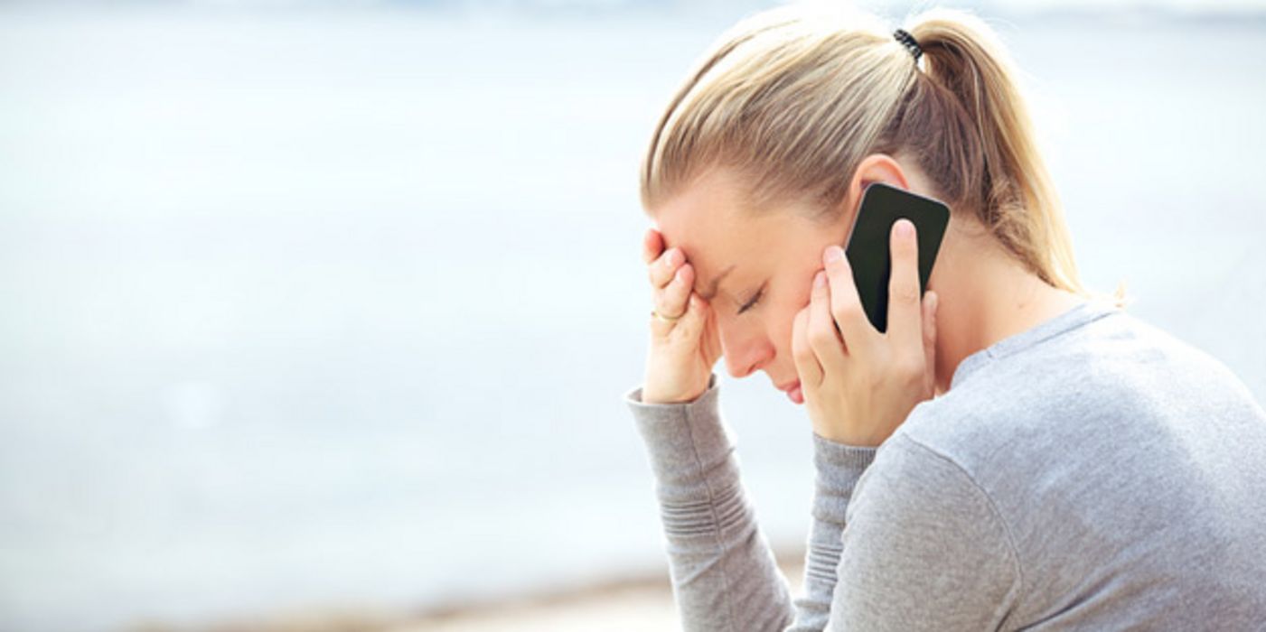 Junge Frau im Profil telefoniert mit besorgter Miene