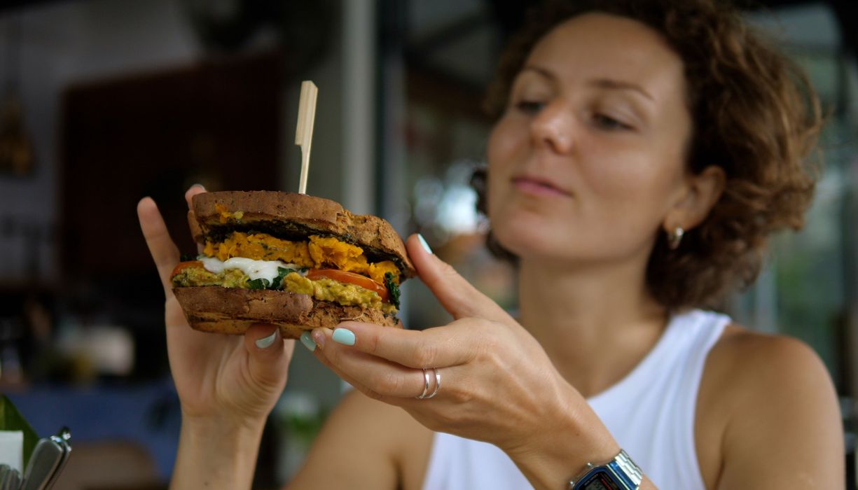 Frau, isst einen vegetarischen Burger.