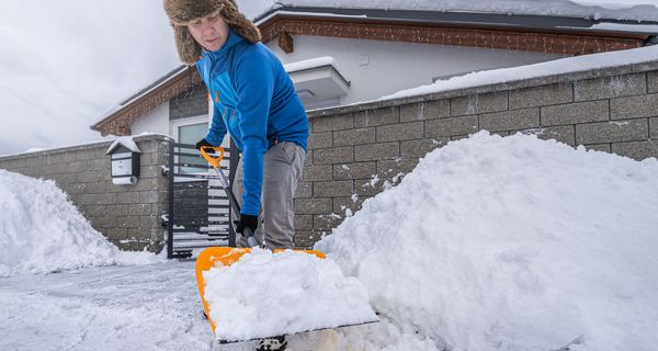 Älterer Mann beim Schneeschippen.