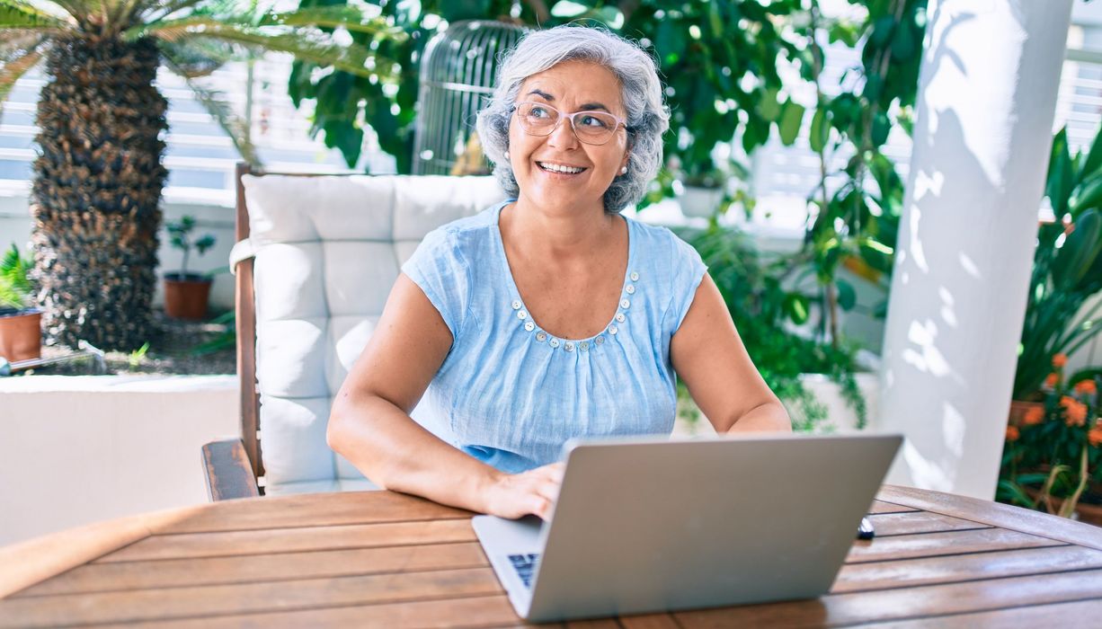 Seniorin, sitzt vor einem Laptop.