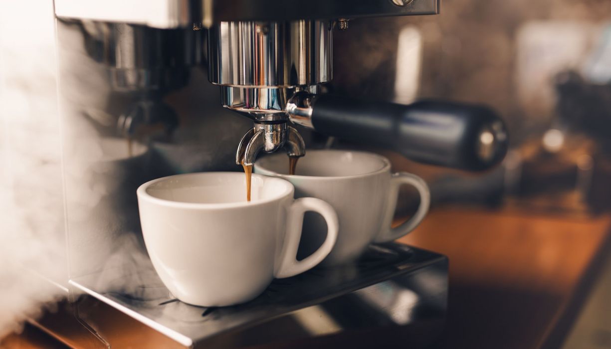 Kaffee, läuft aus einer Siebträgermaschine in zwei Tassen.