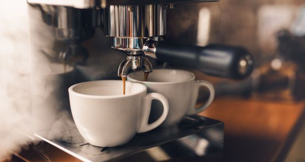 Kaffee, läuft aus einer Siebträgermaschine in zwei Tassen.