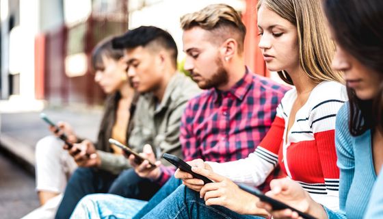 Gruppe Jugendlicher, die auf Smartphones schauen.