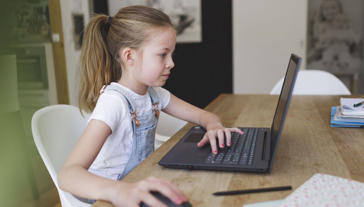 Junges Mädchen, sitzt vor einem Laptop.