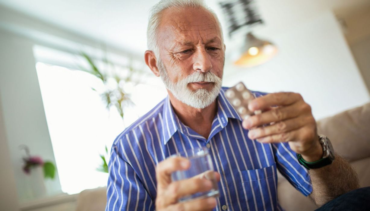 Senior hält eine Packung mit Tabletten in der Hand.