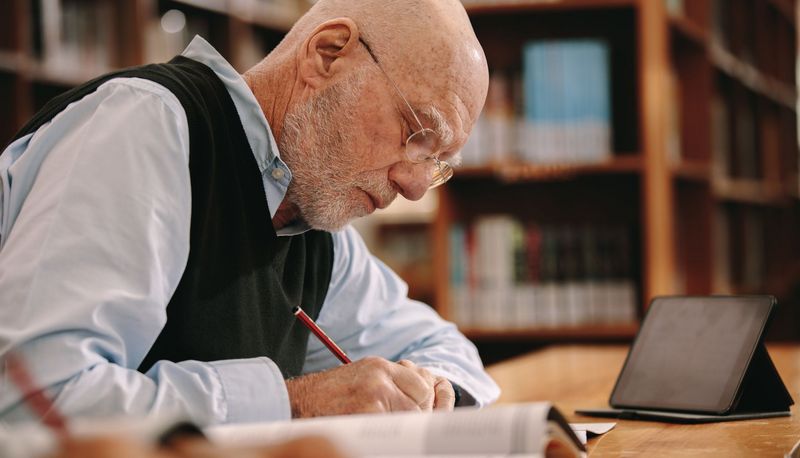 Senior. sitzt in einer Bibliothek und lernt.