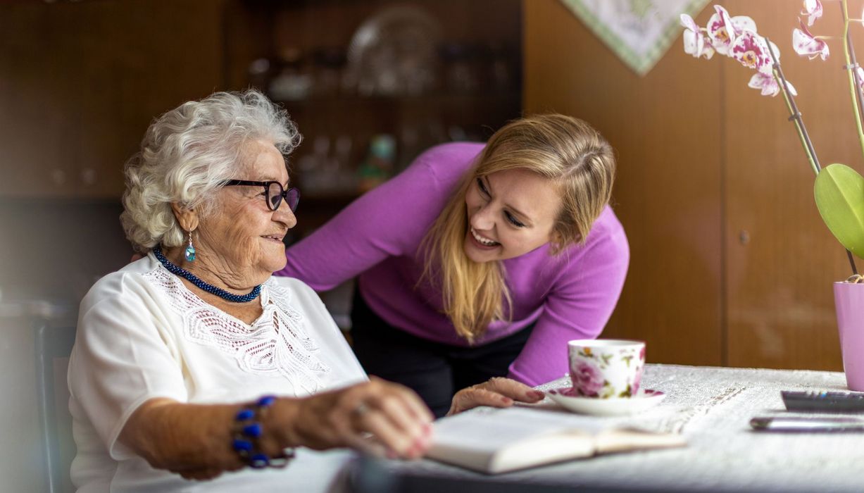 Jüngere Frau kümmert sich um Seniorin.