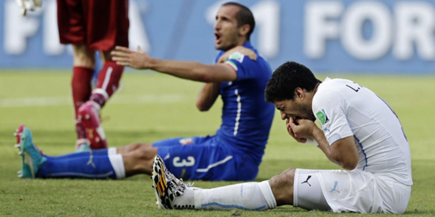 Der Italiener Giorgio Chiellini beklagt sich nachdem Uruguays Spieler Luis Suarez ihn gebissen hat.