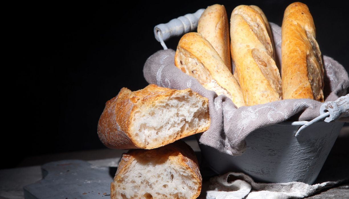 Korb mit Weißbrot vor schwarzem Hintergrund.