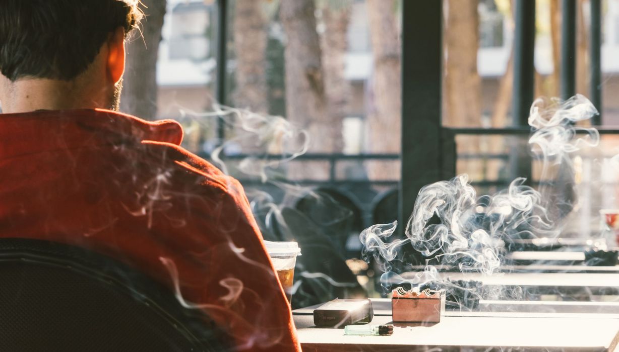 Mann, sitzt in einem Café und raucht.