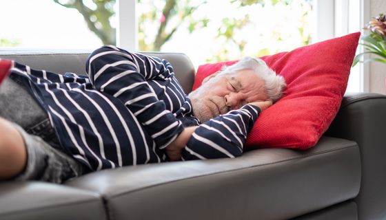 Mann schläft auf einem Sofa.