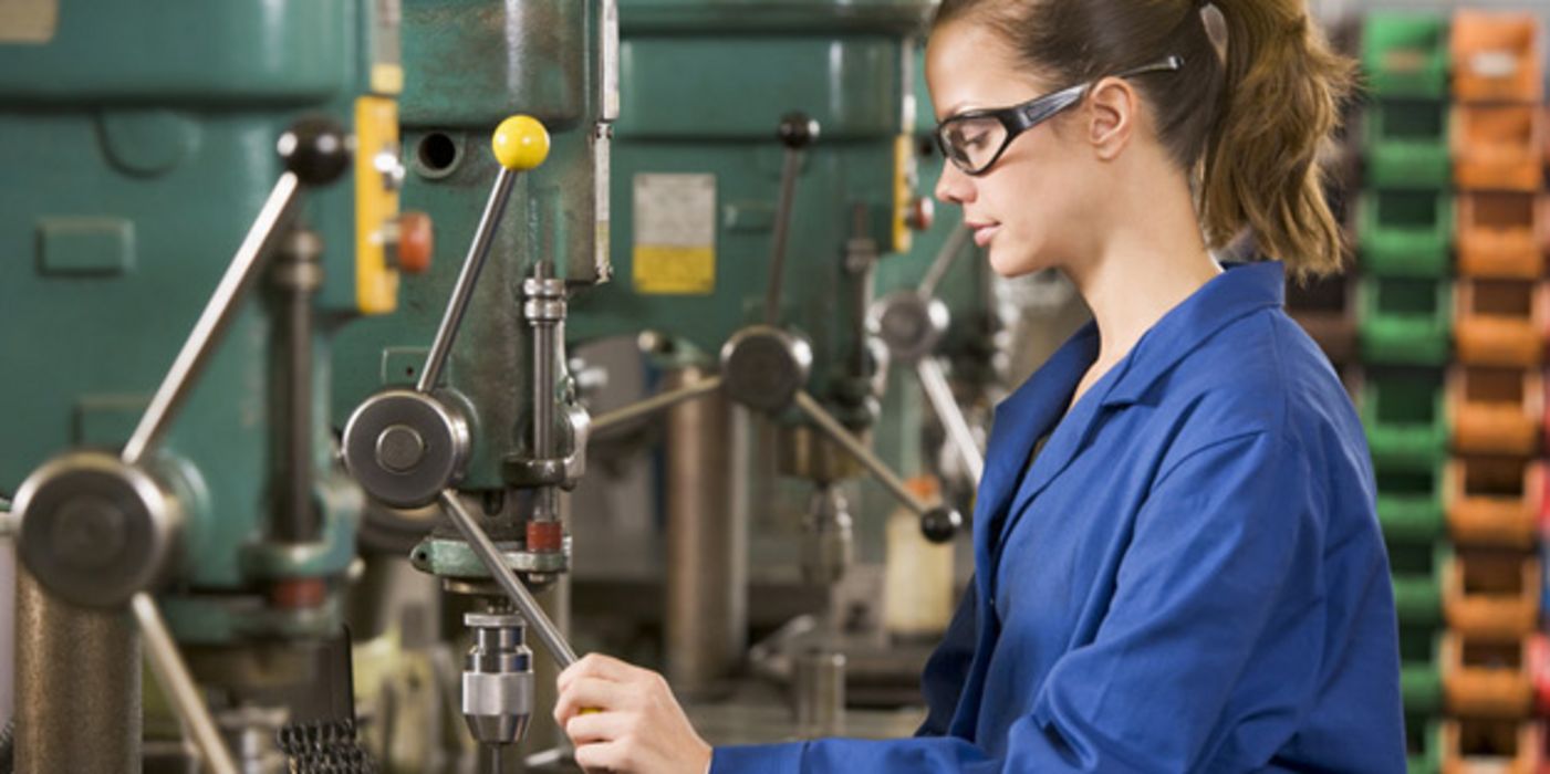 Frau arbeitet an einer Industrie-Maschine