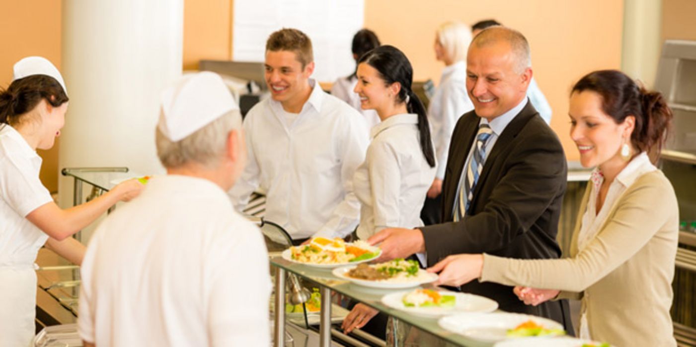 Fröhliche Menschen an der Essensausgabe einer Kantine