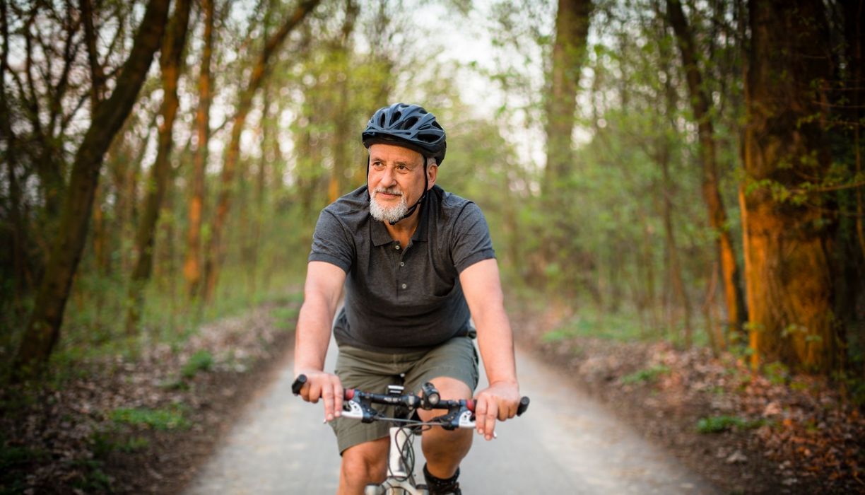 Älterer Mann, fährt in der Natur Fahrrad.