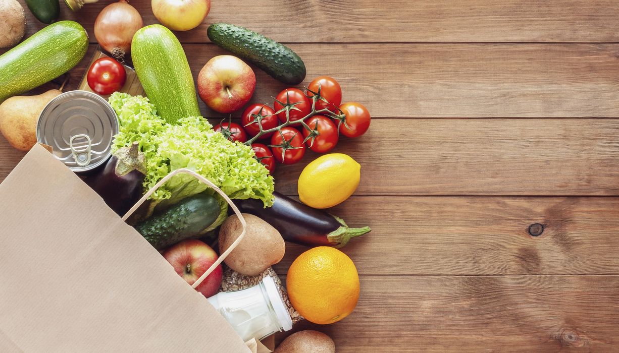 Tüte, aus der Obst und Gemüse herausschaut.