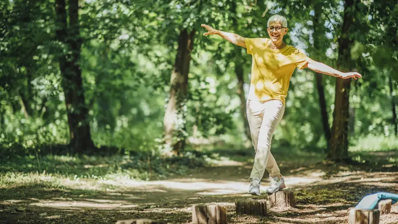 Frau balanciert auf Baumstümpfen im Wald.