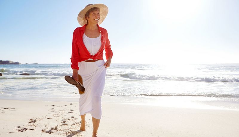 Frau mit Sonnenhut am Strand.