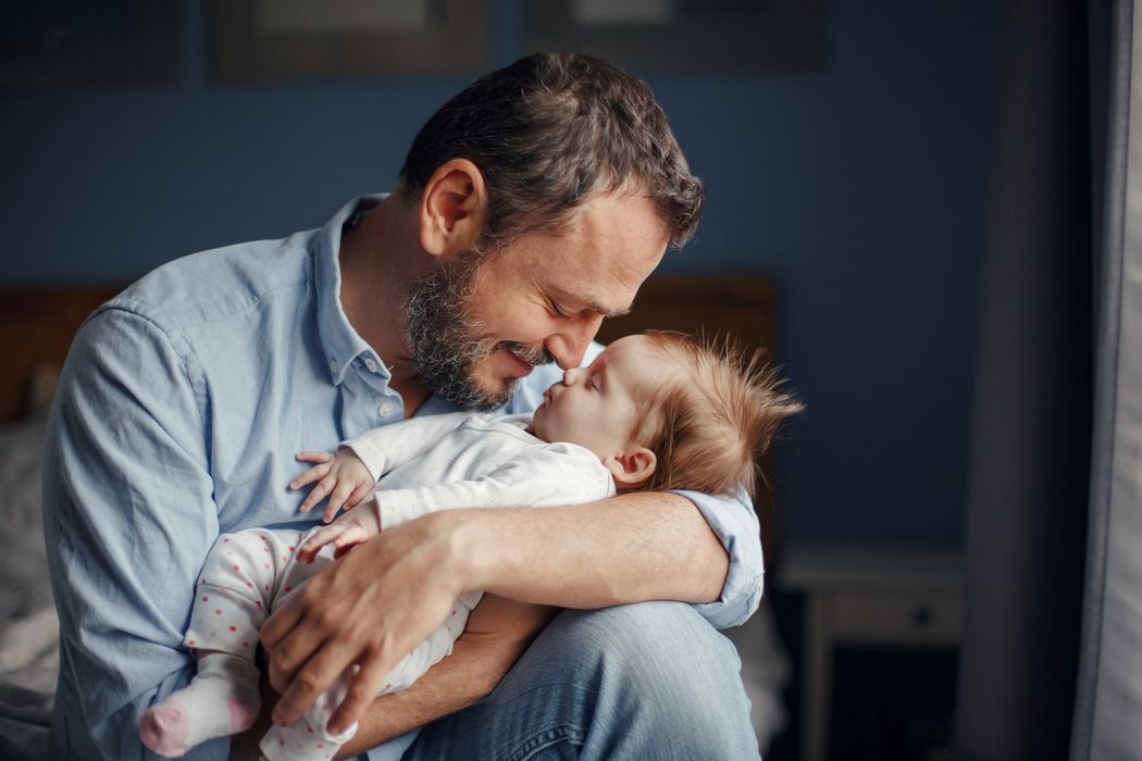 Vater, hält Baby im Arm.