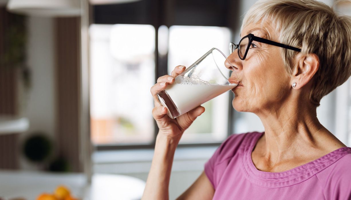 Ältere Frau, trinkt ein Glas Milch.