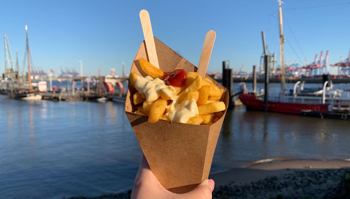 Portion Pommes mit Ketchup und Mayonnaise in einer Papptüte.