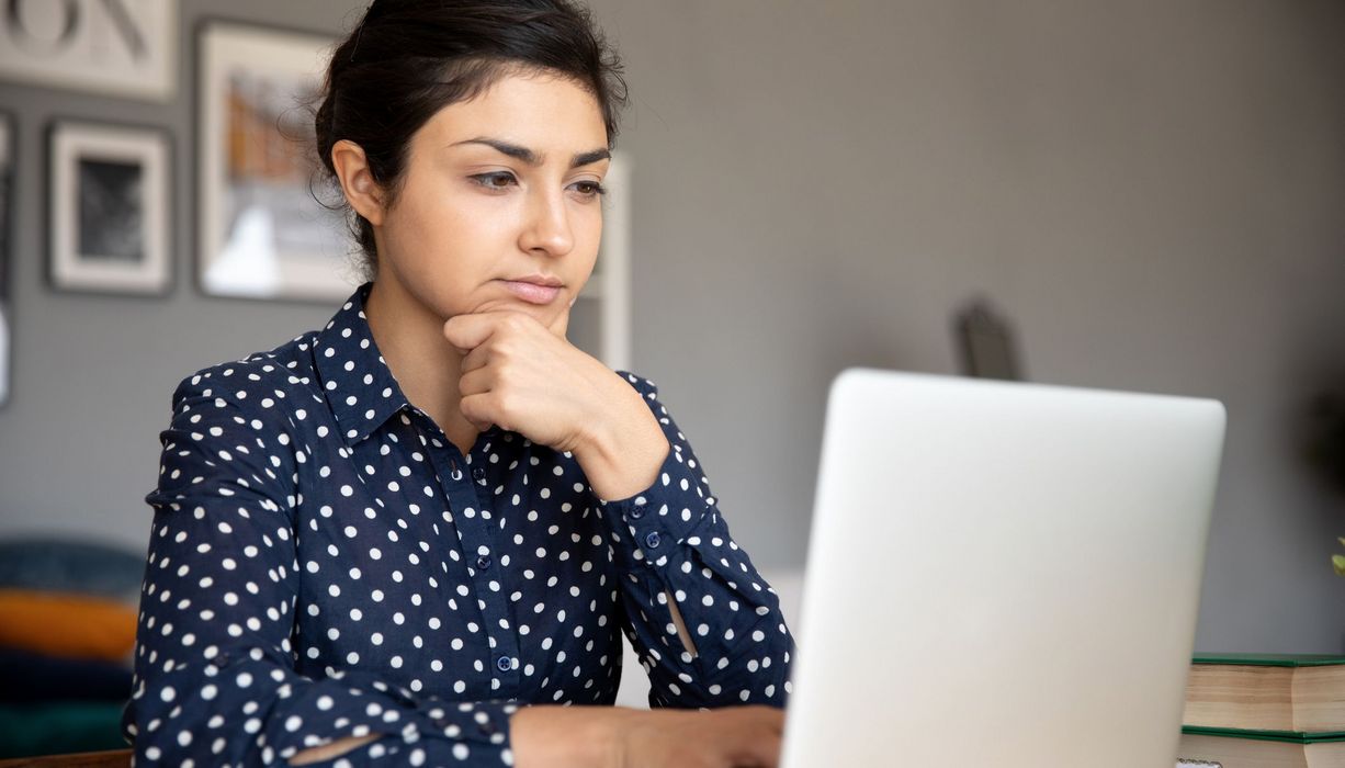 Junge Frau, sitzt vor ihrem Laptop.