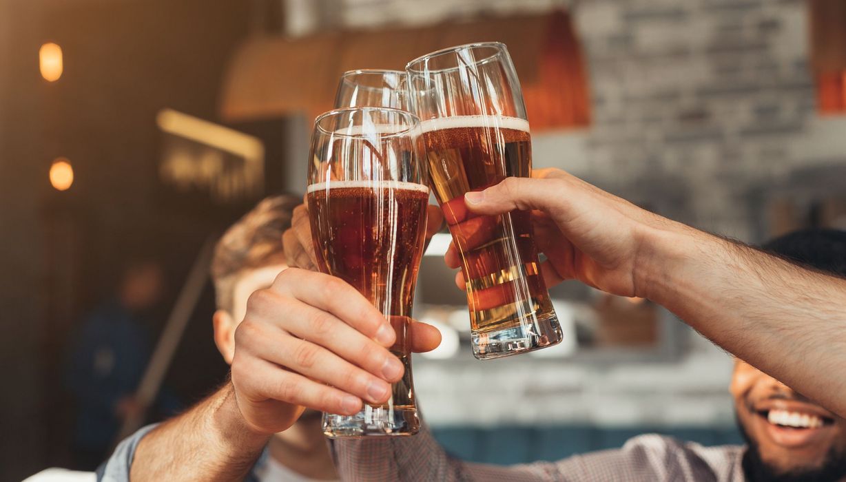 Männer, prosten sich mit einem Bier zu.