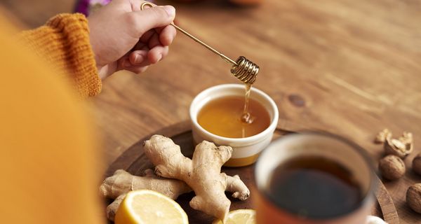Frau, ist dabei, Honig in eine Tasse Tee zu geben.