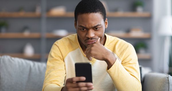 Mann, schaut skeptisch in sein Smartphone.