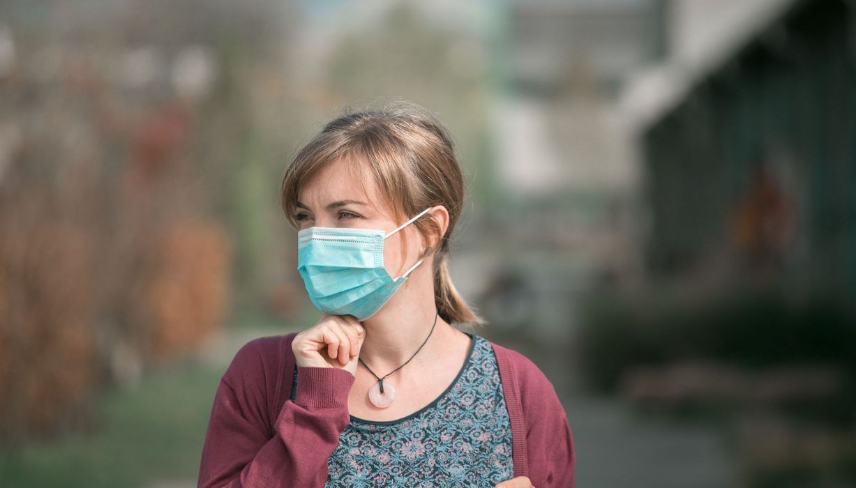 Junge Frau, draußen mit Maske.