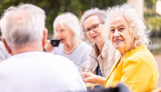 ältere Frau sitzt mit anderen älteren Menschen zusammen