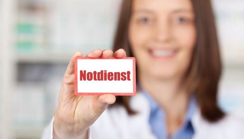 Apothekerin hält ein "Notdienst"-Schild.