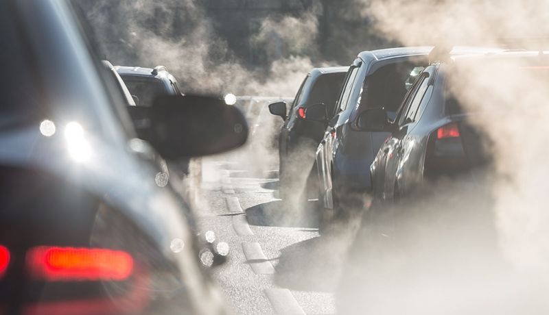 Autos mit Abgasen auf einer Straße.