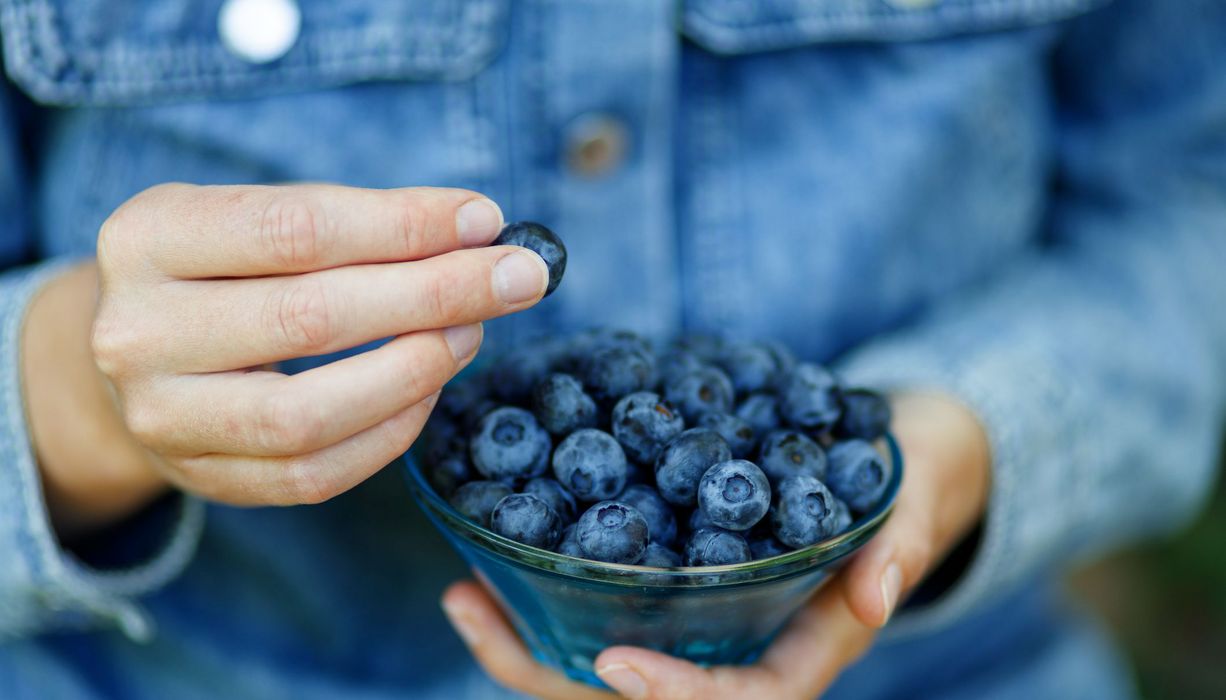 Frau, hält eine Schale mit Beeren in den Händen.