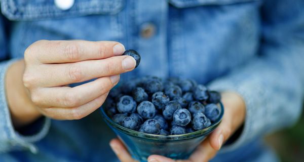 Frau, hält eine Schale mit Beeren in den Händen.