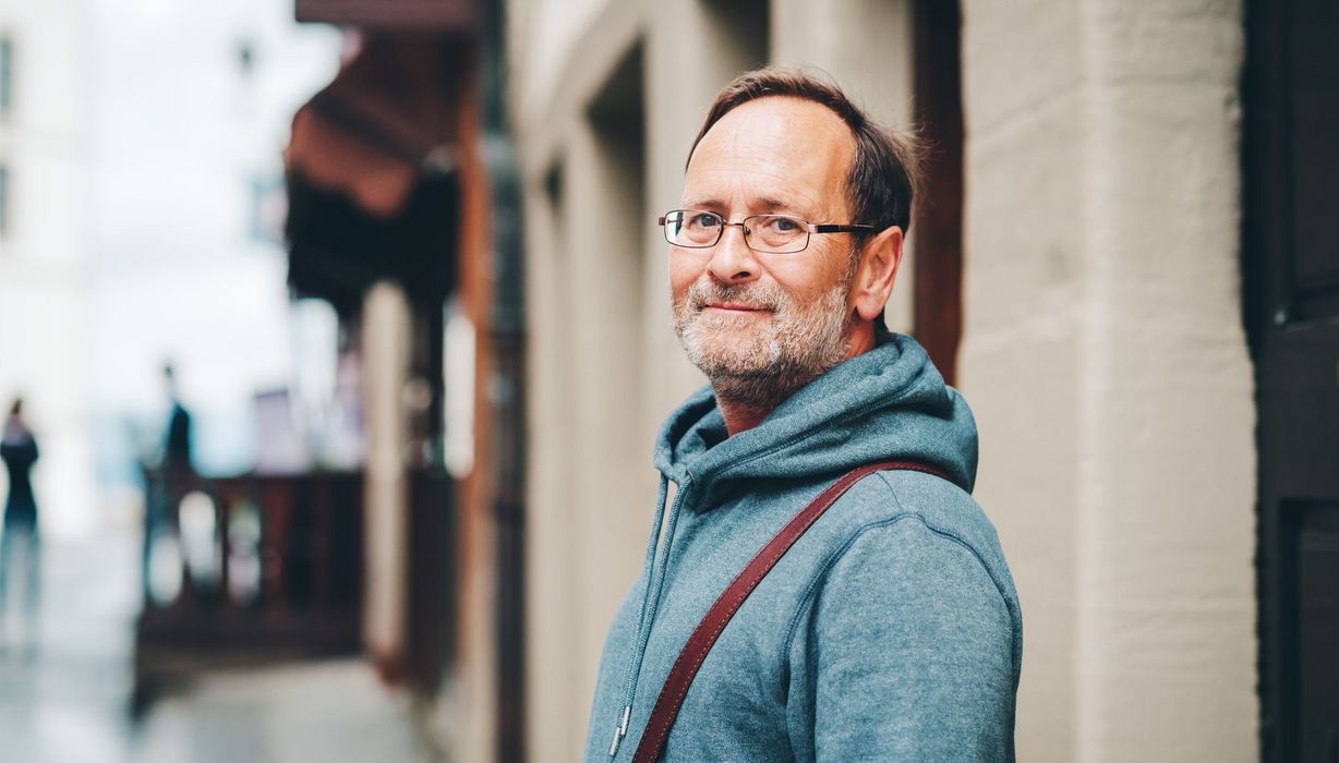 Älterer Mann in Freizeitkleidung auf einer Straße.