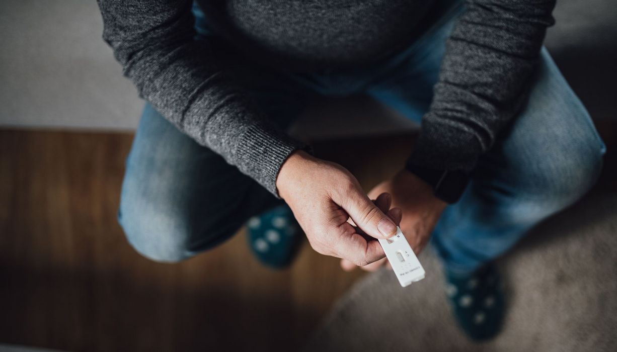 Mann, hält Antigen-Schnelltests in der Hand.