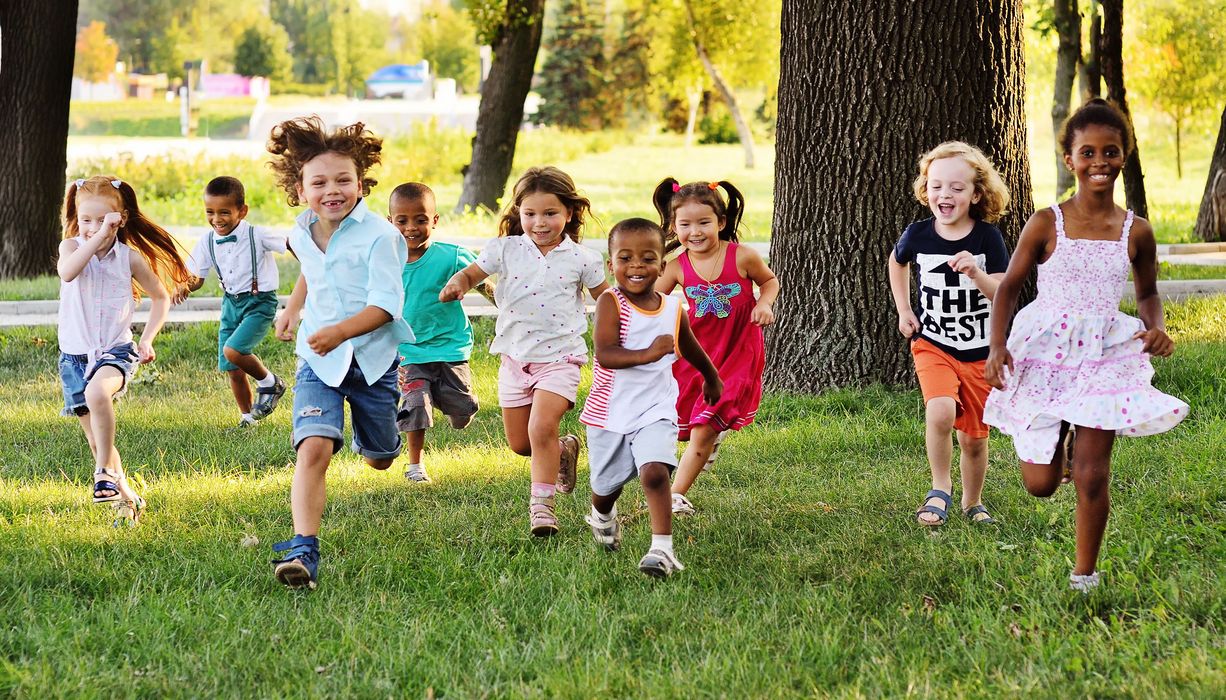 Eine Gruppe Kinder rennt auf einer Wiese.